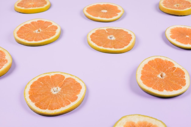 Photo gratuite une tranche d'orange sur fond violet