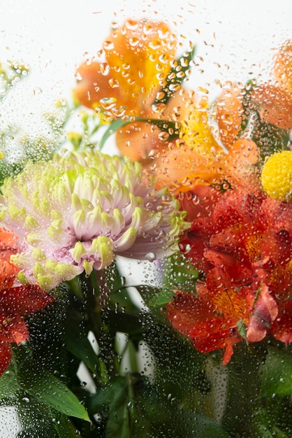 Photo gratuite voir des fleurs à travers le verre condensé