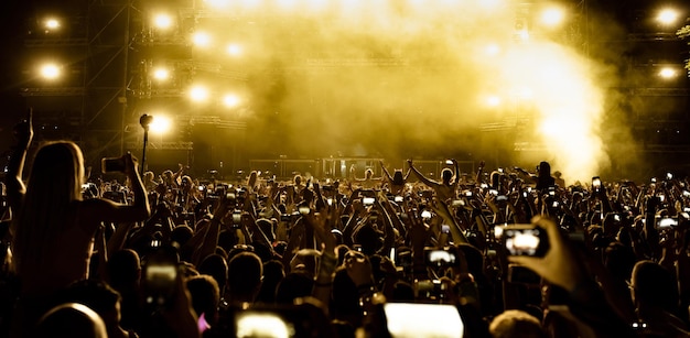 Photo gratuite vue arrière de fans enthousiastes s'amusant au festival de musique et prenant des photos de la scène avec leurs téléphones intelligents copier l'espace