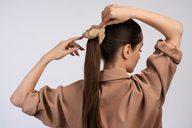 Photo gratuite vue arrière femme attachant ses cheveux