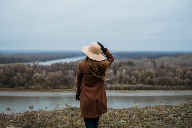 Photo gratuite vue arrière de la femme avec chapeau admirant la vue sur le lac