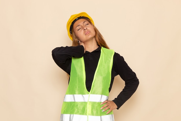 Photo gratuite vue avant femme constructeur en chemise noire casque jaune posant ayant mal au cou sur le mur blanc