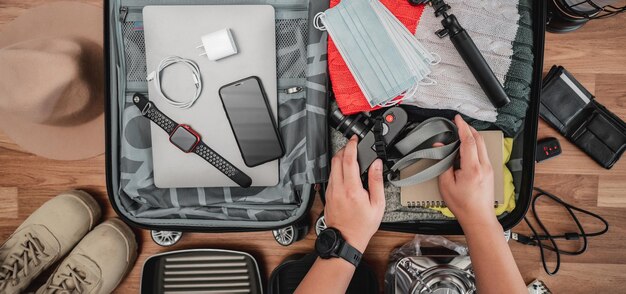 Vue de dessus de la préparation de la valise pour les vacances d'été Jeune homme vérifiant les accessoires et les trucs dans les bagages Voyage vacances et vacances concept