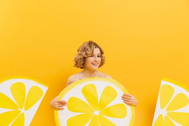 Photo gratuite vue de face de femme souriante posant avec des tranches de citron décor