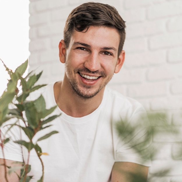 Photo gratuite vue de face de l'homme souriant assis à côté de plantes