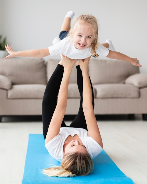 Photo gratuite vue de face de la mère exerçant avec un enfant heureux à la maison