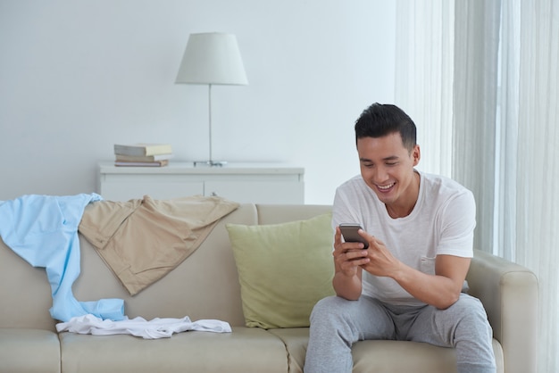 Vue de face de textos homme à des amis à la maison et souriant