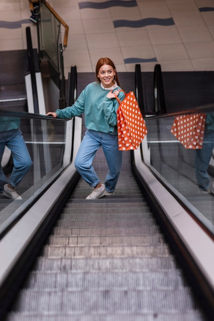 Photo gratuite vue frontale, femme, tenue, papier, sac, sur, escalator