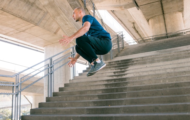 Photo gratuite vue latérale, de, actif, jeune, athlète masculin, sauter par-dessus, escalier