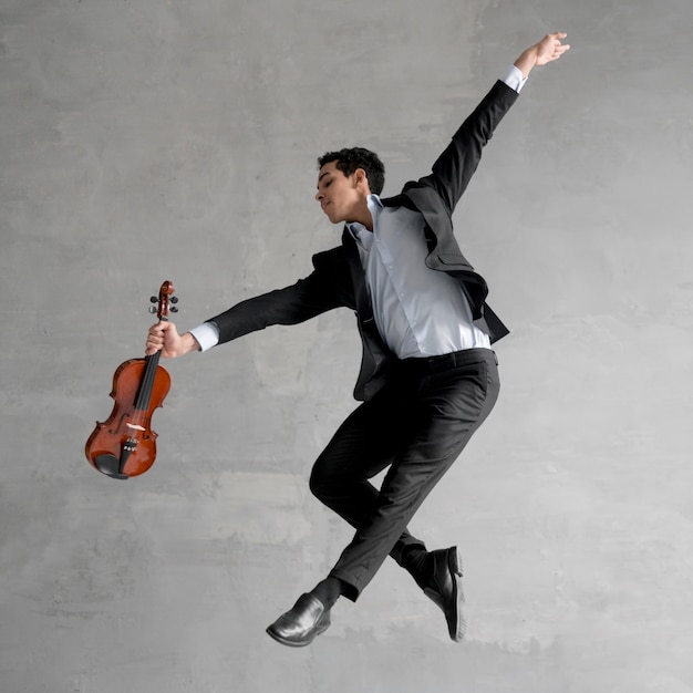 Photo gratuite vue latérale du musicien masculin tenant le violon et posant en l'air