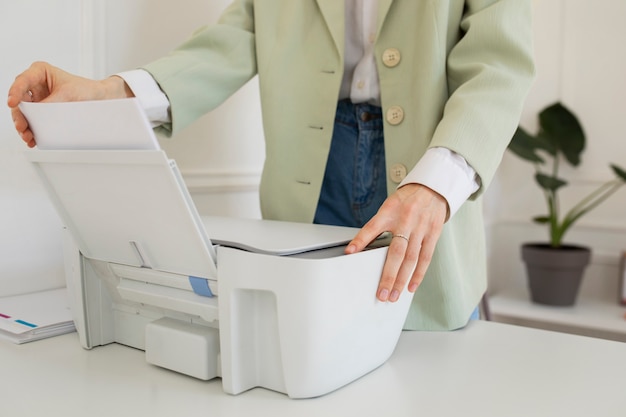 Photo gratuite vue latérale femme à l'aide d'une imprimante de bureau