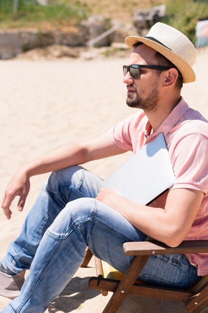 Vue latérale de l'homme avec un ordinateur portable à la plage