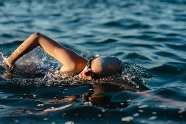 Photo gratuite vue latérale de la nageuse avec bonnet et lunettes nageant dans l'eau