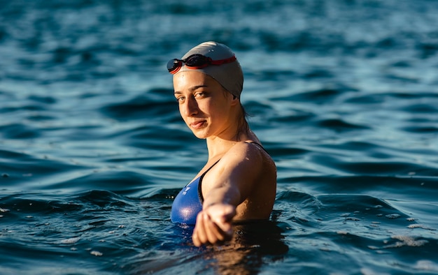 Photo gratuite vue latérale de la nageuse avec bonnet et lunettes posant tout en nageant dans l'eau