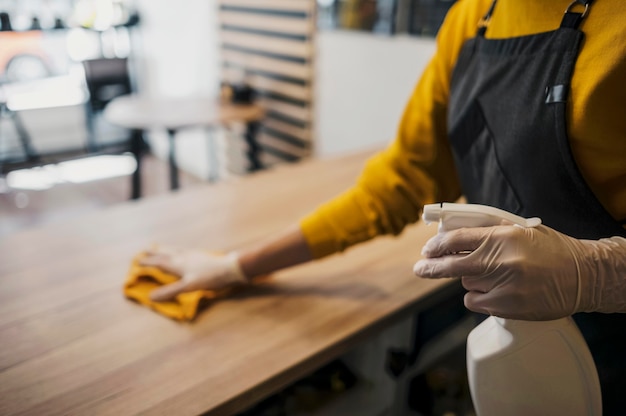 Photo gratuite vue latérale de la table de nettoyage femme barista tout en portant des gants en latex