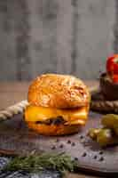 Photo gratuite vue lointaine avant hamburger de viande au fromage avec cornichons, légumes verts et tomates sur le bureau en bois