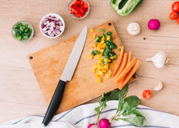 Photo gratuite une vue de la planche à découper avec couteau et légumes sur le bureau en bois