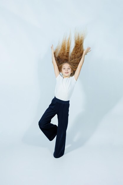 Photo adolescente aux cheveux longs en t-shirt blanc et jeans bleus et souriante isolée sur un fond gris vêtements élégants pour filles