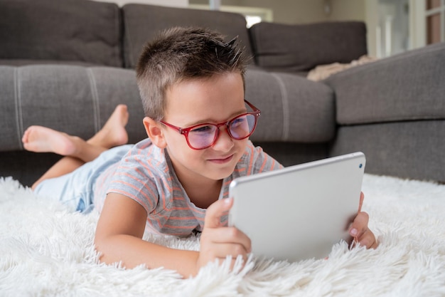 Adorable petit garçon à l'aide d'une tablette numérique sur le sol à la maison