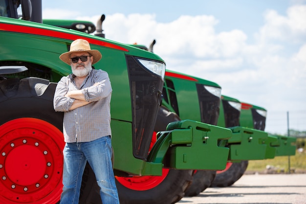 Photo un agriculteur avec un tracteur, combine dans un champ au soleil. couleurs confiantes et lumineuses