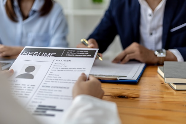 Photo l'ambiance de la salle d'entretien dans la start-up, le candidat remet le curriculum vitae à l'enquêteur comme pièce justificative pour l'entretien, deux enquêteurs. notion d'entretien d'embauche