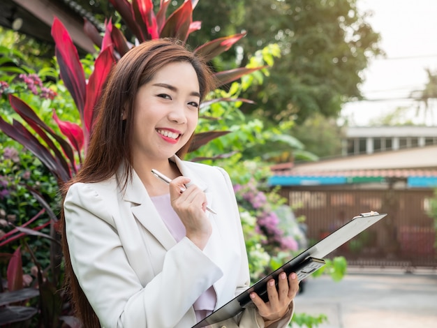 Asiatique, femme affaires, tenue, documents, dossier, debout, dehors Souriante jeune femme d'affaires réussie.