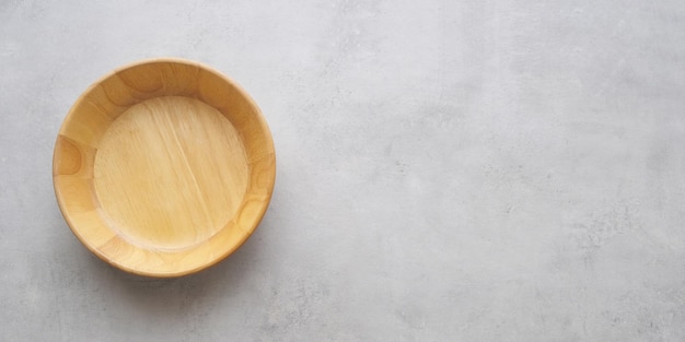 Assiette en bois ronde vide sur fond de table en ciment gris