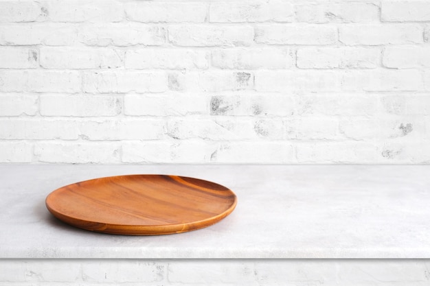 Assiette en bois ronde vide sur table en ciment blanc et fond de mur