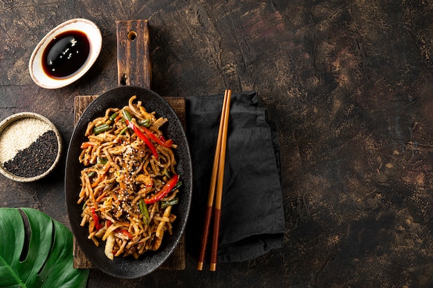 Assiette de nouilles soba asiatiques au sarrasin avec légumes, champignons et poulet sur fond sombre