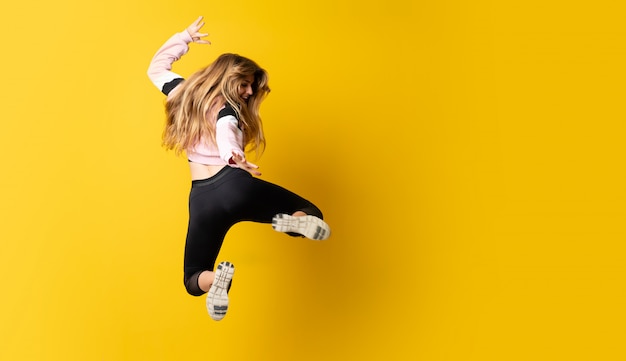 Photo ballerine urbaine danser sur fond jaune isolé et sauter