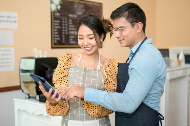 Photo baristas utilisant une tablette vérifiant les revenus de l'entreprise, marketing d'entreprise réussi dans un café