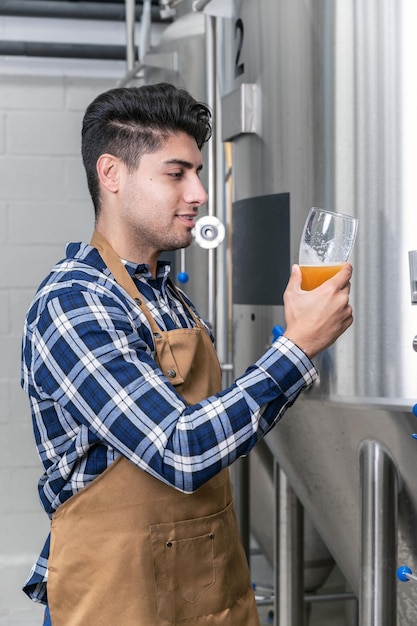 Beau brasseur en tablier testant la bière à la brasserie