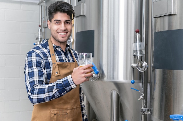 Beau brasseur en tablier testant la bière à la brasserie