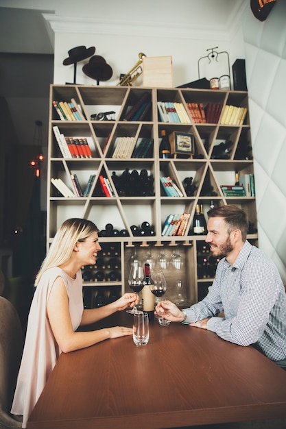 Beau jeune couple à la date assis à table dans le bar à vin