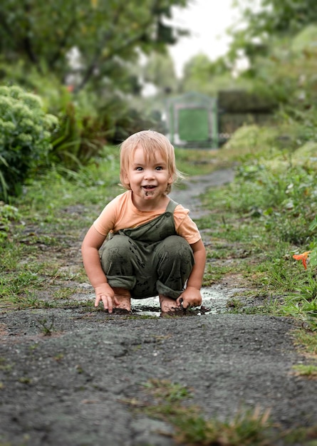 Bébé avec un charmant sourire joue dans une flaque d'eau