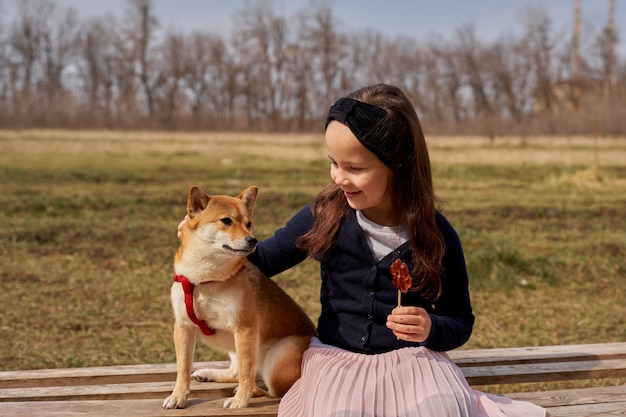 Photo belle fille avec un bonbon joue avec un chien