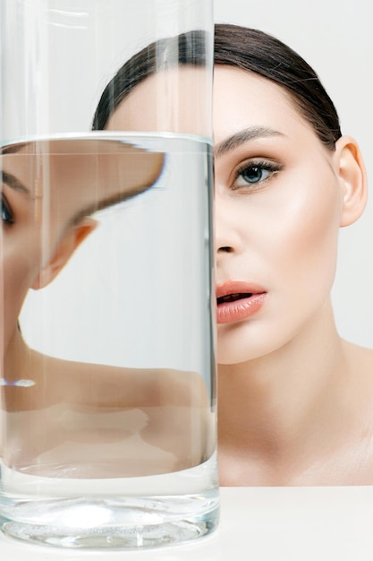 Photo belle fille en bouteille avec de l'eau propre peau jolie jeune femme et verre