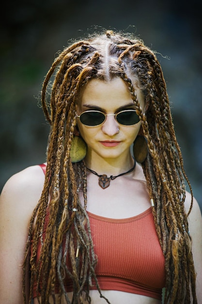 Photo belle fille avec des dreadlocks habillé style hippie pose à l'extérieur