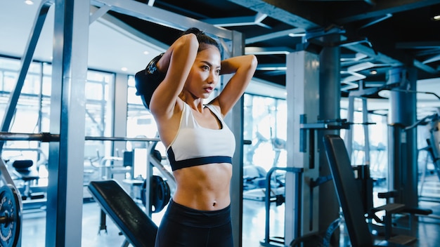 Belle jeune femme asiatique faisant soulever des haltères en classe de fitness