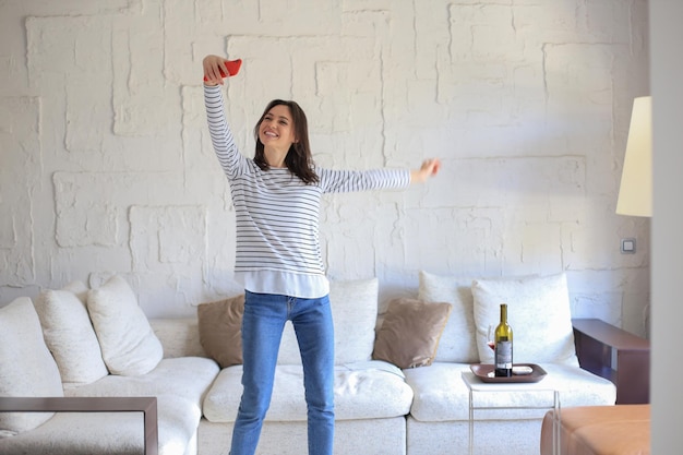 Photo belle jeune femme prenant selfie avec smartphone à la maison près du canapé