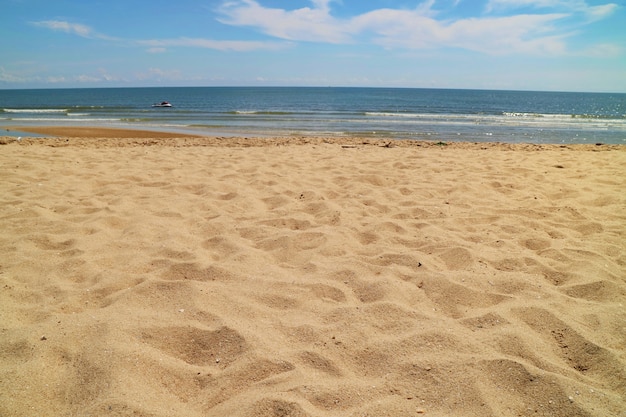 La belle plage de sable, vague et ciel bleu en été