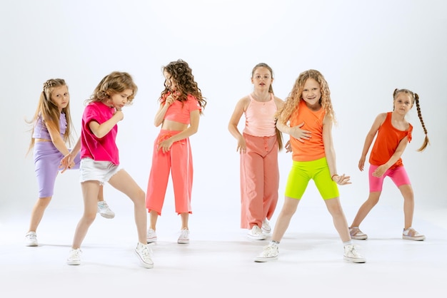 Belles filles élégantes enfants formation de danse s'amusant isolé sur fond de studio blanc