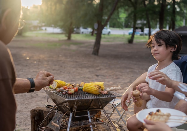 Bonne famille asiatique ayant un barbecue ensemble. Cuisiner un barbecue grillé pour le dîner pendant le camping sur la plage d'été.