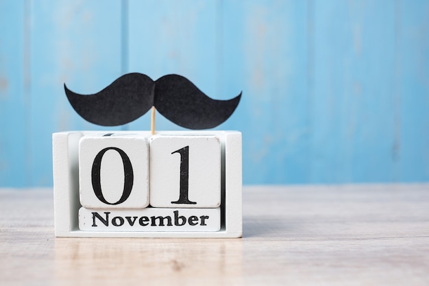 Photo calendrier du 1er novembre et moustache sur table en bois. père, journée internationale des hommes, sensibilisation au cancer de la prostate