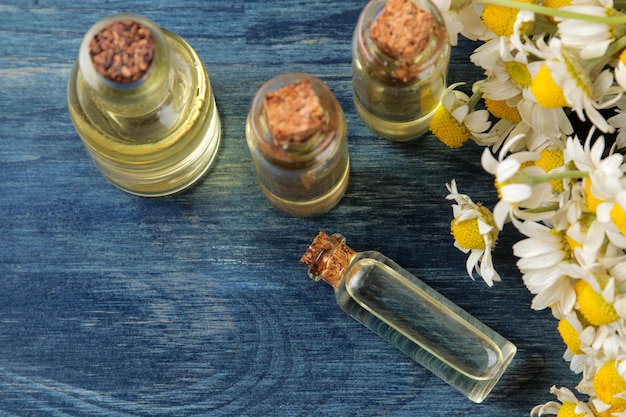 Camomille médicinale et extrait de camomille dans une bouteille d'huile de fleurs de camomille aromathérapie un médicament sur une table en bois bleu vue de dessus place pour le texte