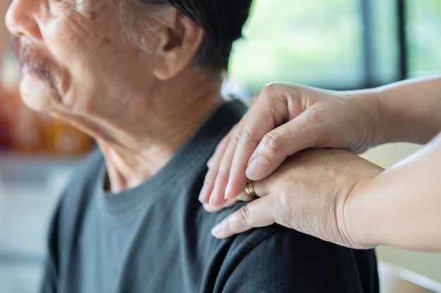 Photo capture de filles main sur l'épaule de pères asiatiques plus âgés avec amour et soin concentration sélective sur les mains