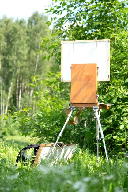 Photo le chevalet de l'artiste se tient parmi la verdure d'été