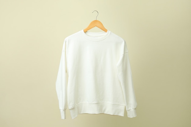 Cintre avec sweat-shirt blanc contre surface beige