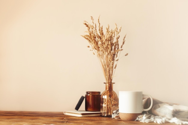 Composition confortable d'automne. Une tasse de café, un plaid, une bougie, des fleurs séchées sur fond clair.