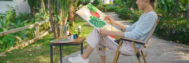 Photo concept d'art créatif artiste féminine assise dans un parc et peignant une image sur toile avec bonheur